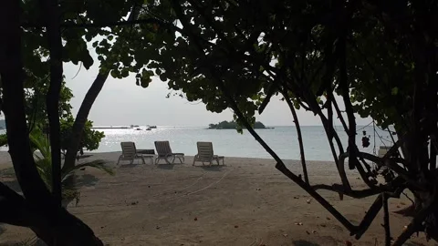 Static shot of beach chairs on seashore and boat in Maldives Stockbeeldmateriaal 277535968