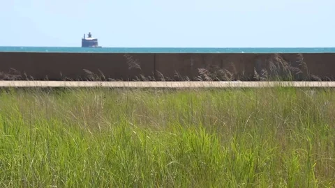 STATIC SHOT OF BIKE PATH, LAKE AND TWO PEOPLE ON BIKES CROSS FRAME L-R Stock Footage 106127241