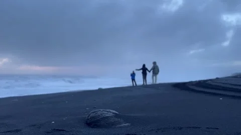 Static shot of black sand beach with small rock in foreground and distant p.. Stock Footage 327683796