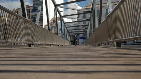 Static shot of a Caucasian millennial man walking on a pedestrian bridge. Stock Footage 122373496