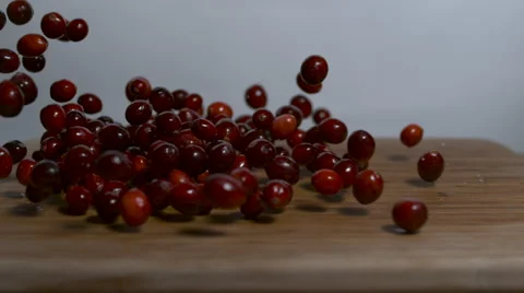 Static shot of cranberries being dropped onto a cutting board in slow motion. Stock Footage 64361519