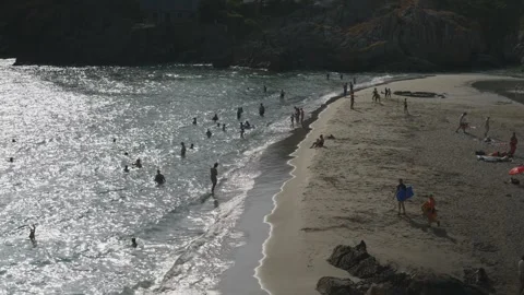 Static shot of crowded beach with swimmers and sunbathers on sunny summer day Stock Footage 341363449