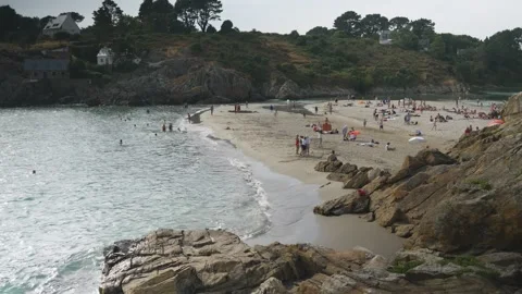 Static shot of crowded rocky cove beach with turquoise water, overcast sky Stock Footage 341314331