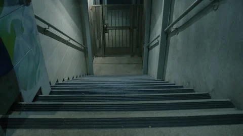Static shot of dimly lit stairs going down to metal grate. Staircase down  Stock Footage 286263206