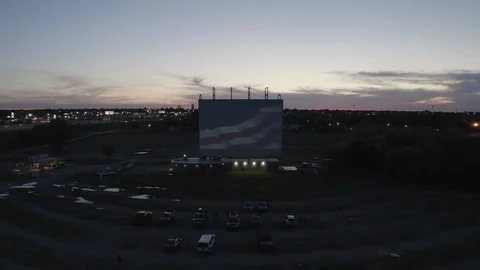 Static shot of drive-in theater at dusk w/American Flag on screen Stock Footage 112762273
