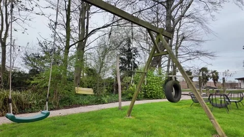 Static shot of an empty wooden swing set on a green lawn. Vídeos de archivo 333192487