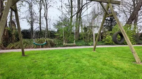 Static shot of an empty wooden swing set on a green lawn. Vídeos de archivo 333192488