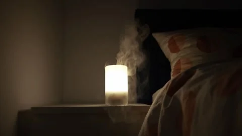 Static shot of an essential oil diffuser on a nightstand emitting a warm Stock Footage 273081054