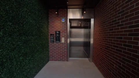 Static shot of exterior elevator opening and closing in brick corridor Stock Footage 332630076