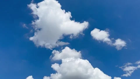 Static shot of fluffy white cumulus clouds drifting across a deep blue sky. Видео 345665118
