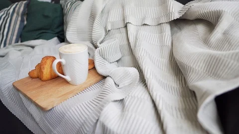 Static shot - fresh coffee and a hot croissant on a large sofa with pillows Stock Footage 114158176
