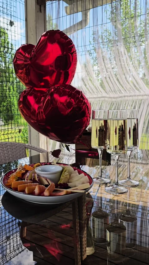 Static shot of heart balloons and food platter in sunny outdoor cafe Stock Footage 346622254