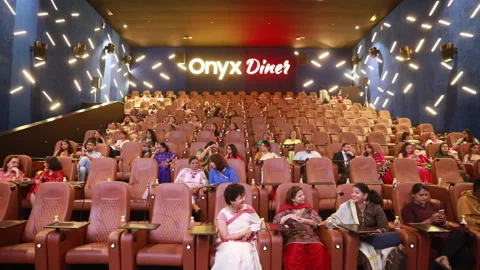 Static shot of large crowd sitting and socialising at a movie theatre Stock Footage 137156011