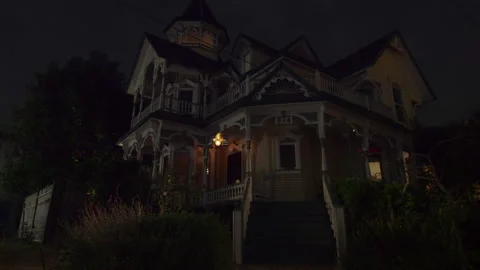 Static shot of large Victorian house on the corner at night, porch light is on Stock Footage 202911940