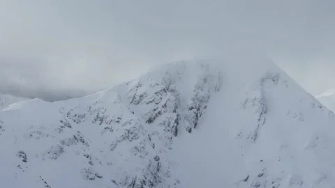 Static shot of low cloud moving around the summit of snow covered mountain Stock Footage 133017336