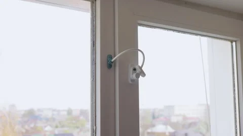 Static shot of a man installing a child safety window lock with a power drill Stock Footage 333104642