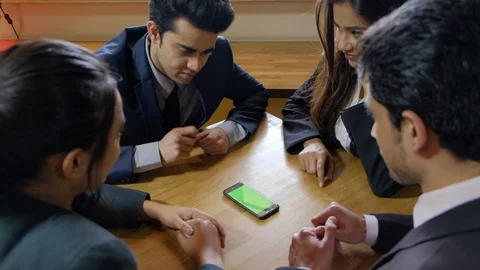 Static shot of a mobile phone touch screen in green as the Indian colleagues aro Stock Footage 104530976