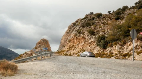 Static shot of a mountain road with cliffs, two cars are passing by. Stock Footage 121262467
