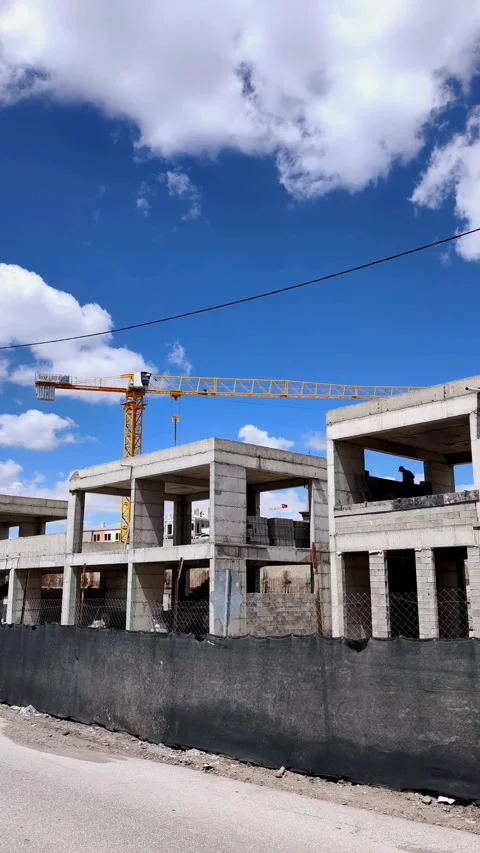 Static shot of a multi-story concrete structure under construction. A worker is Stockbeeldmateriaal 333908412