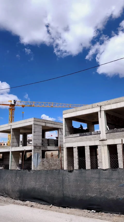 Static shot of a multi-story concrete structure under construction. A worker is Stockbeeldmateriaal 333908422