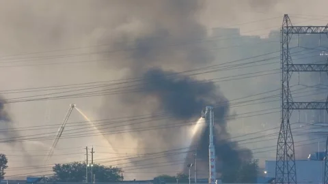 Static shot of multiple firefighter crews tackling a large blaze at a Stock Footage 252056095