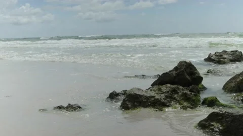 Static shot of ocean waves washing over sea rocks with a big sky in the backg Stock Footage 139216272