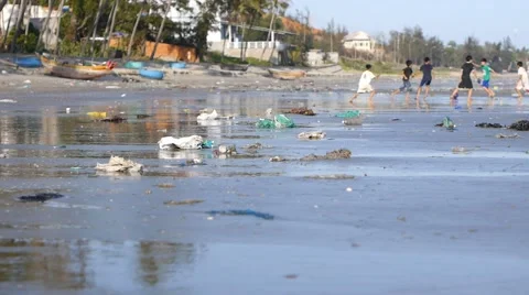 Static shot of playing children in defocus on beach polluted by trash Stock Footage 50789017