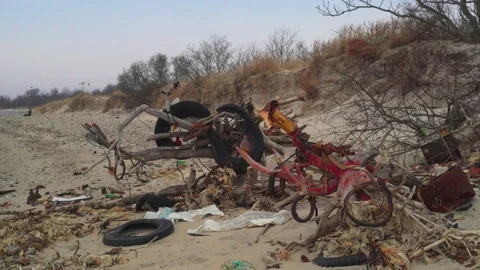 Static shot of the polluted sandy beach with tires and other trash debris. Vídeo Stock 89860294