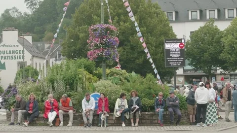 Static shot of seated crowd at cherry festival in overcast Breton town square Stock Footage 341314500