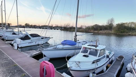 Static shot of small white boats moored at a wooden dock during dusk. Vídeos de archivo 332860939