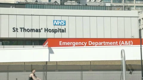 Static shot of St Thomas Hospital and NHS logo with several cyclists, red Stock Footage 130240954