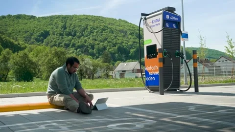 Static Shot Sunny Day Software Engineer Working Laptop EV Charging Station Stock Footage 334826317