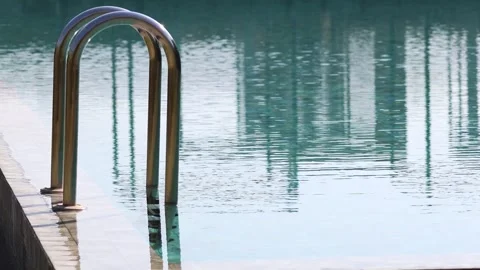 Static shot of swimming pool ladder with turquoise water reflecting tall ci.. Vídeos de archivo 332592324