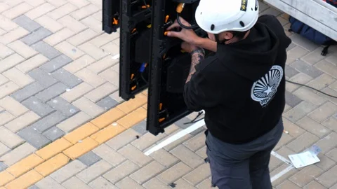 Static shot of a technician assembling lcd panels for a big outdoor screen Stock Footage 123370236