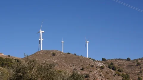 Static shot of three windmills on top of a hill in Mediterranean landscape Stock Footage 120029785