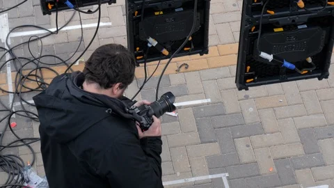 Static shot videographer filming preparations of the stage of an outdoor event Stock Footage 123368825