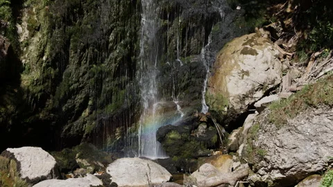 Static shot of Wasserlochklamm waterfall with a bright rainbow in the water.. Stock Footage 341099296