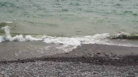 Static shot of water wave hitting a rough beach with coarse brown sand Stock Footage 244734138