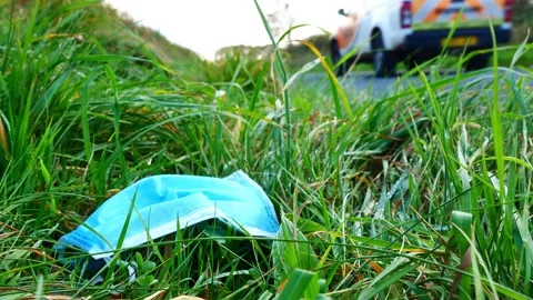 Static shot of a worn surgical mask, left as litter on a country lane Stock Footage 143013795