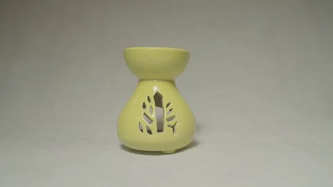 Static shot of yellow ceramic aroma diffuser with tree-shaped cutout design on Stock Footage 309644688