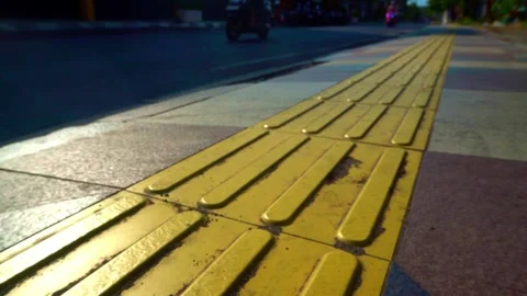 Static shot of yellow tactile paving blocks guiding a sidewalk path along a.. Stock Footage 342030684