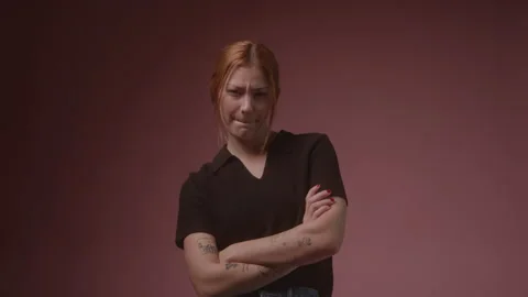 Static shot of Young Caucasian Grumpy Woman in studio with red background Stock Footage 222005807