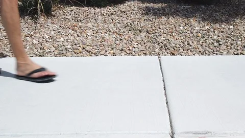 Static, slow motion shot of a males feet, with flip flops, walking into Stock Footage 107076098