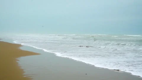 Static slow motion shot of the ocean with calm waves reaching the shore of a Stock Footage 284444850