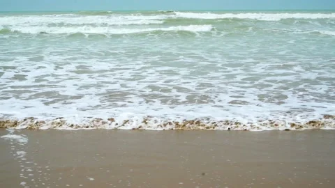 Static slow motion shot of the ocean with calm waves reaching the shore of a Stock Footage 284445075