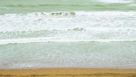 Static slow motion shot of the ocean with calm waves reaching the shore of a Stock Footage 284445230