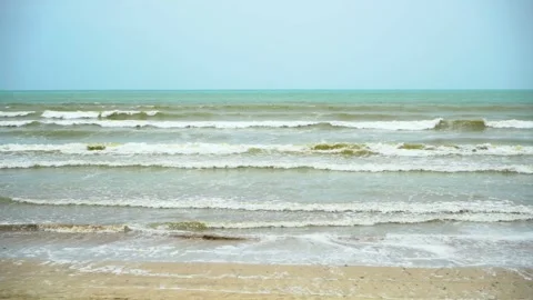 Static slow motion shot of the ocean with calm waves reaching the shore of a Stock Footage 284445235