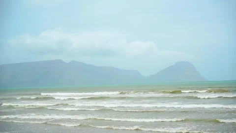 Static slow motion shot of the ocean with calm waves reaching the shore of a Stock Footage 284445273