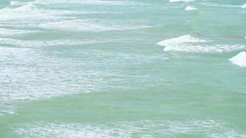Static slow motion shot of the ocean with calm waves reaching the shore of a Stock Footage 284445831