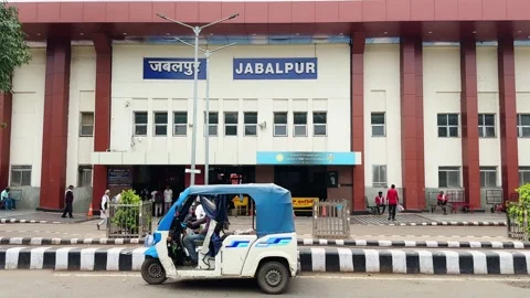 Static street view of an auto rickshaw passing the entrance of Jabalpur Railway Stock Footage 342167012